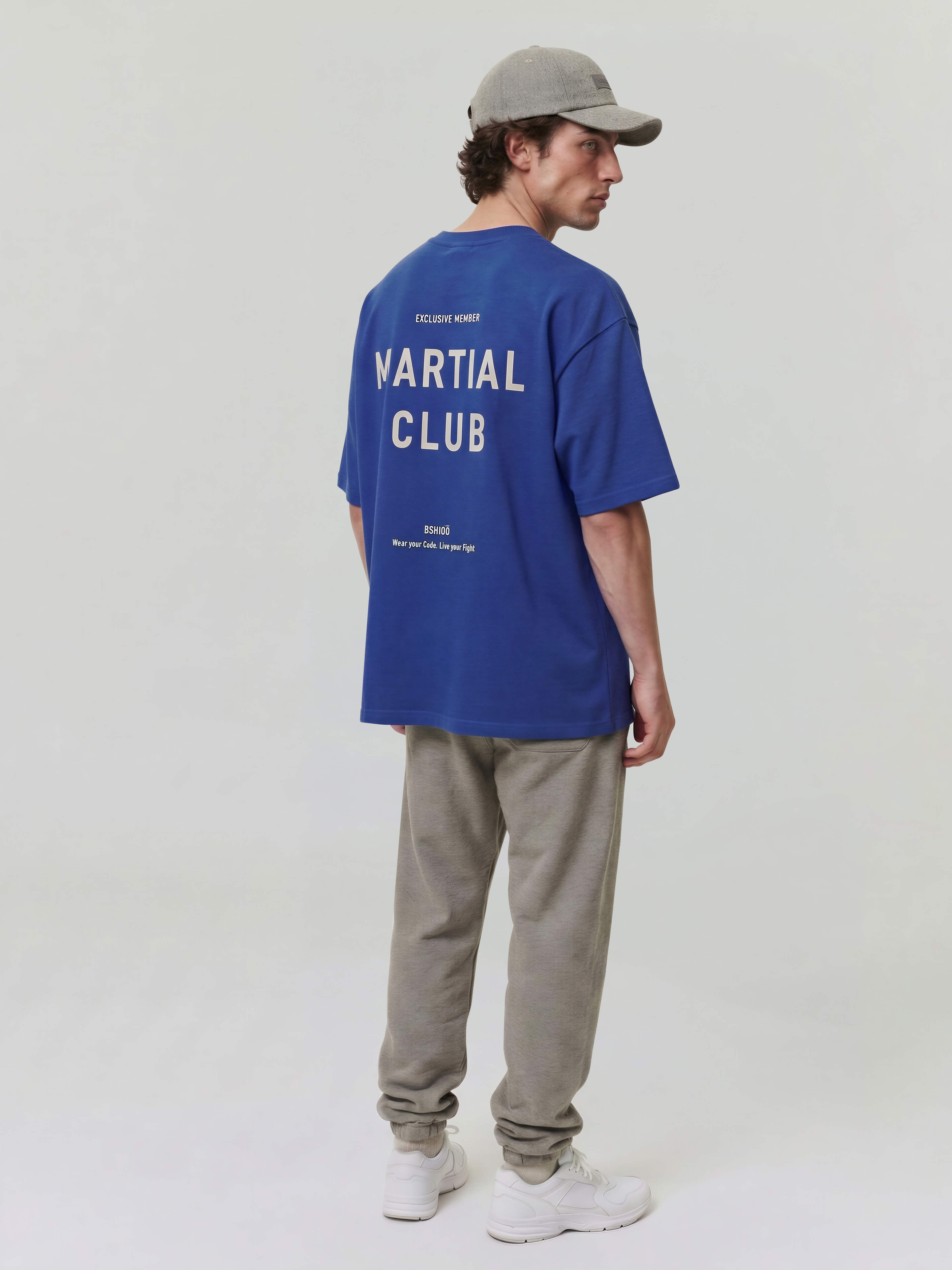 Male model wearing blue oversized Bshido t-shirt back angled full body view with “Martial Club” print
