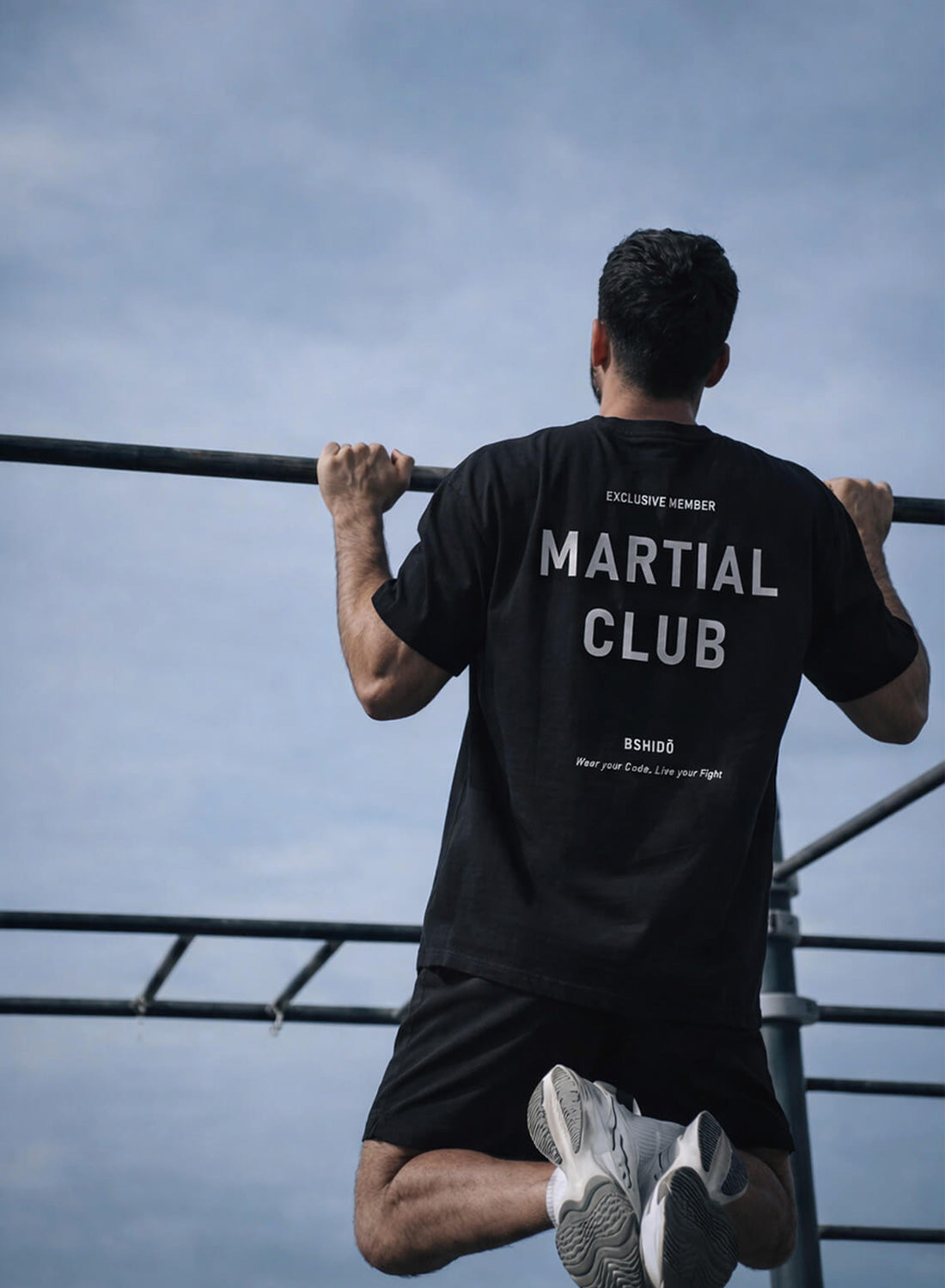 Man doing pull-ups wearing a ‘Martial Club’ Bshidō t-shirt outdoors.