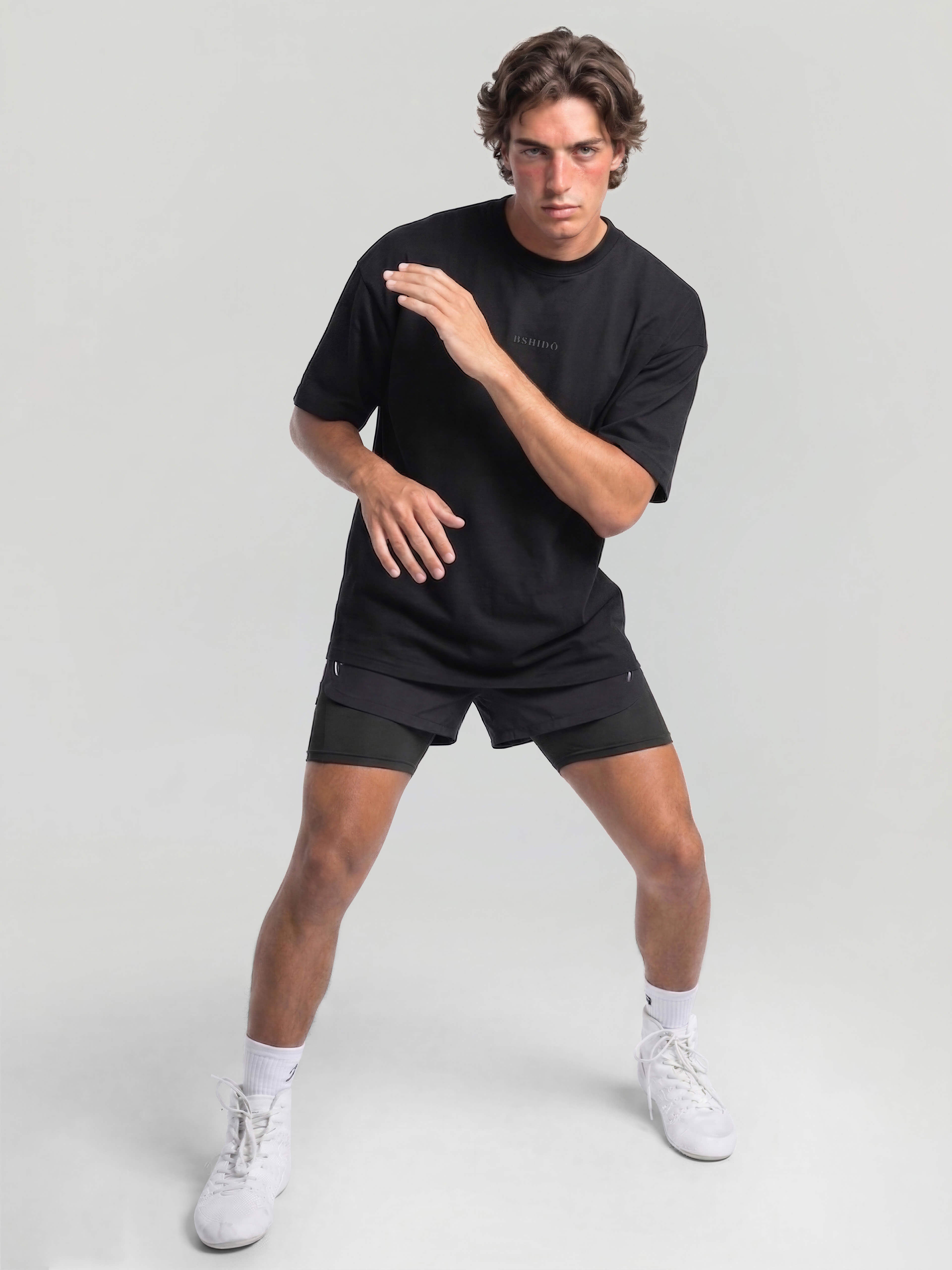 Male model wearing black oversized Bshido t-shirt front view in fighting stance with black shorts
