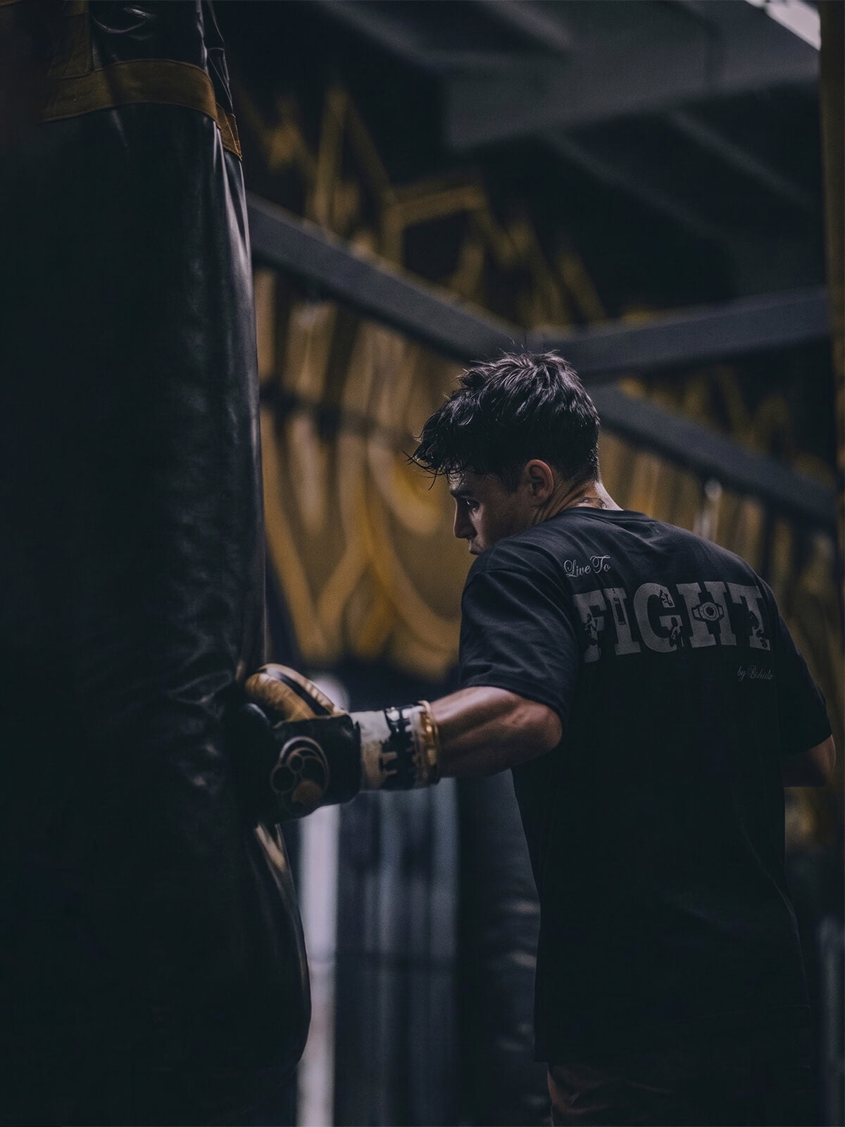 Boxer training with a heavy bag wearing a ‘Live to Fight’ Bshidō t-shirt.