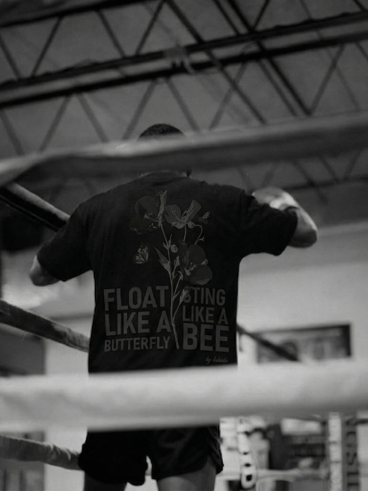 Boxer wearing a t-shirt with “Float like a butterfly, sting like a bee” print in a boxing ring.