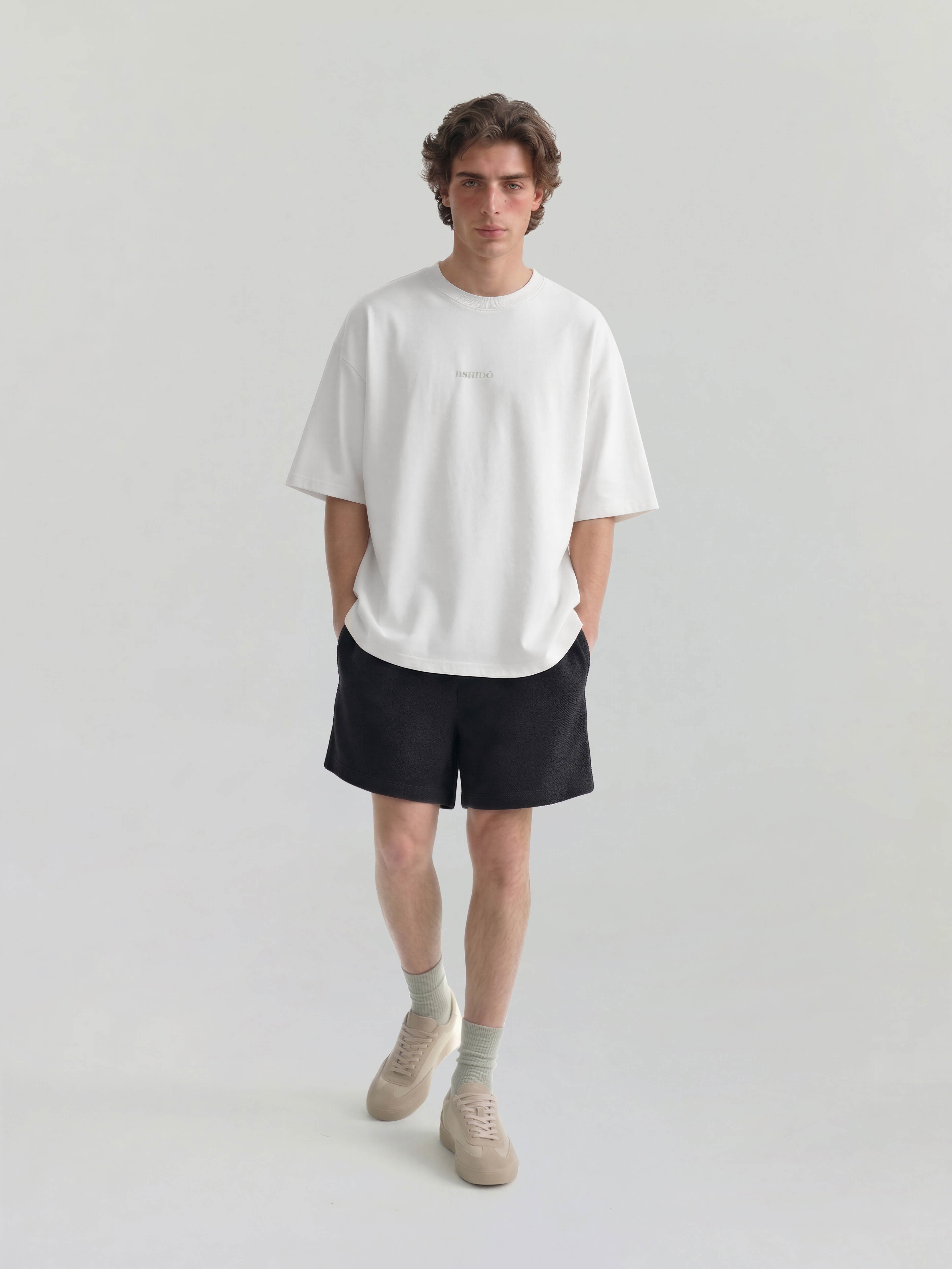Male model wearing white oversized Bshido t-shirt front full body view with black shorts
