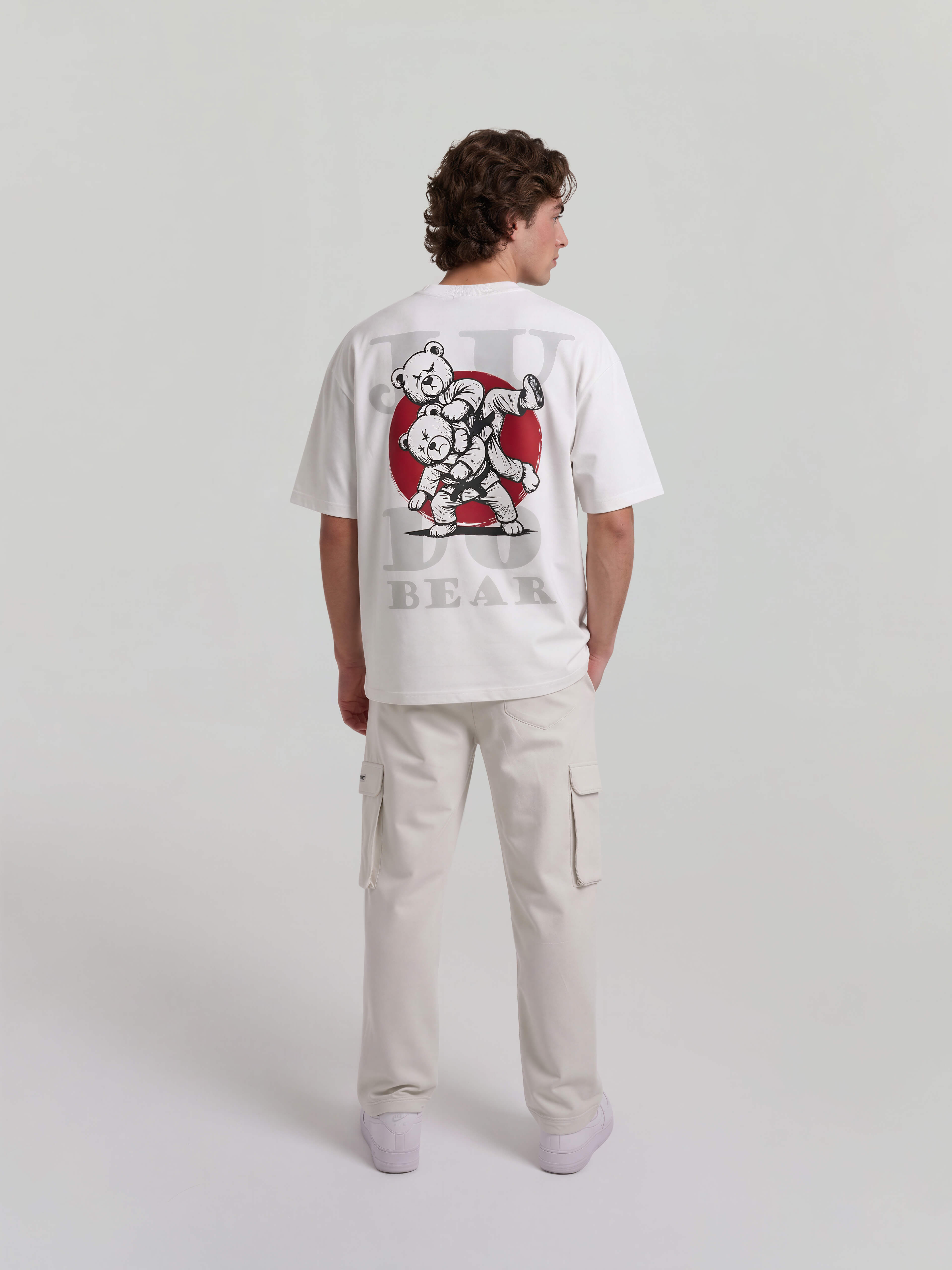 Male model wearing white oversized Bshido t-shirt back full body view with judo bear graphic and red circle print