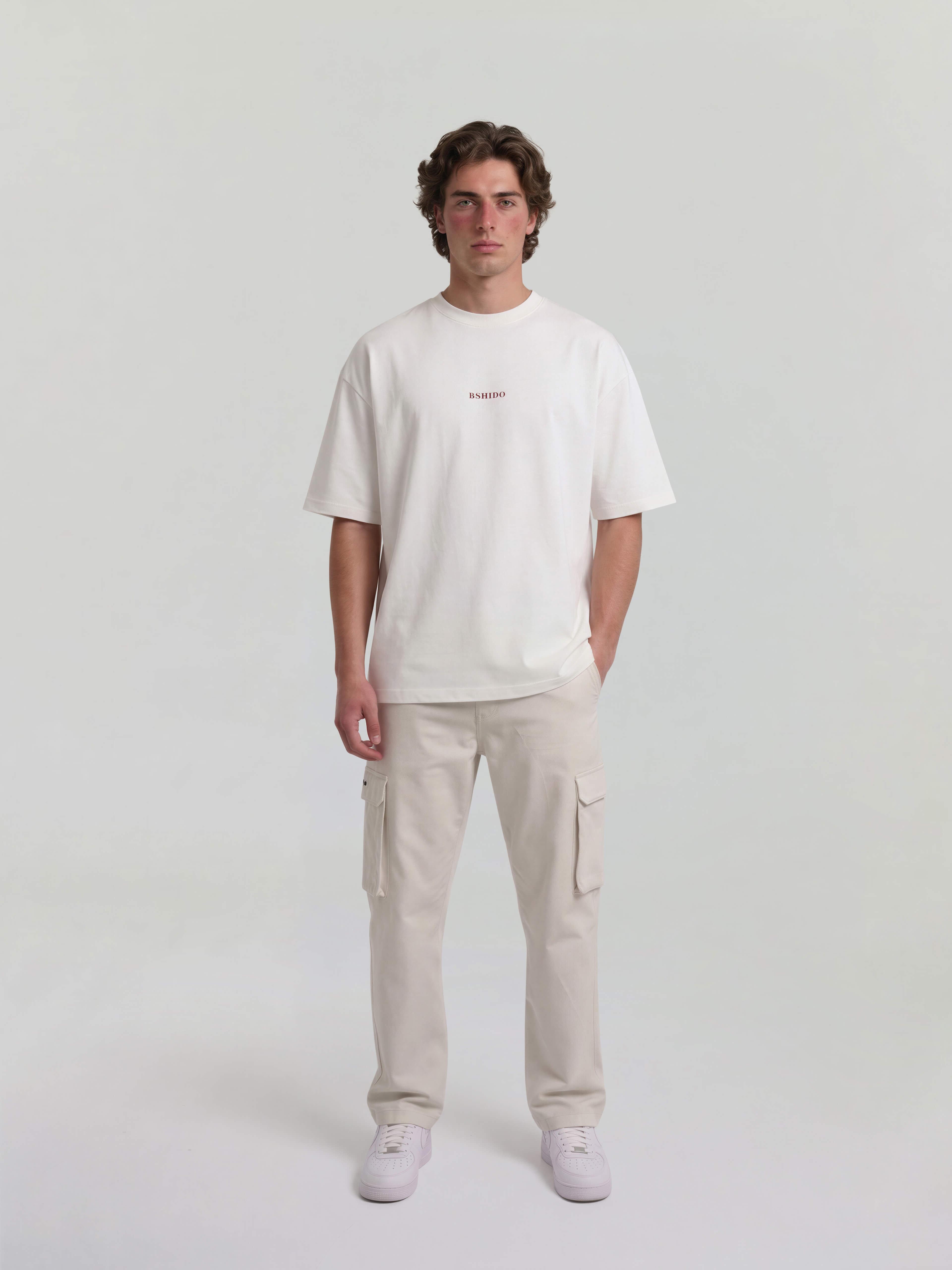 Male model wearing white oversized Bshido t-shirt front full body view with minimal Bshido logo