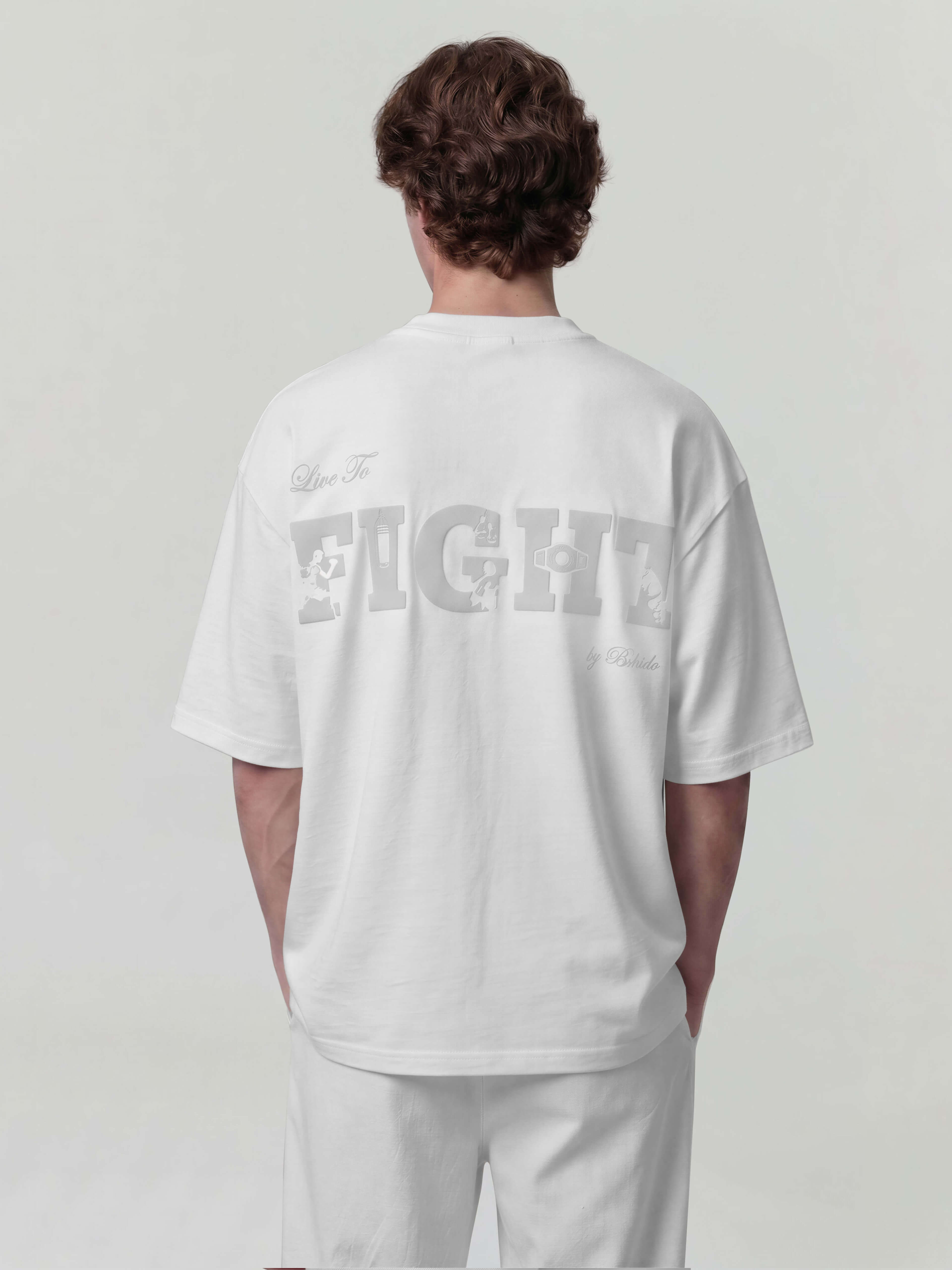 Person wearing a white t-shirt with text 'Live to Fight' on the back against a plain background