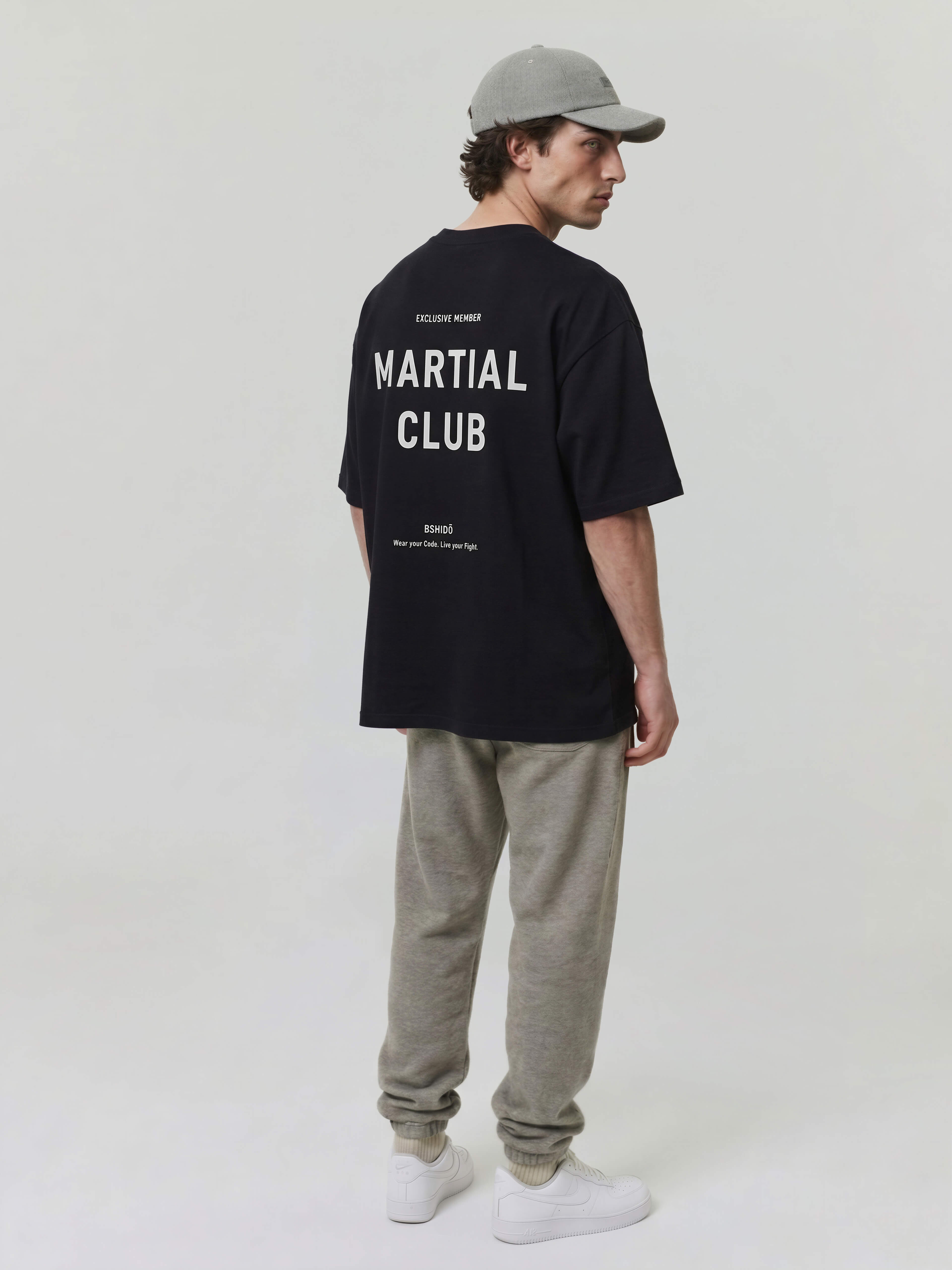 Male model wearing black oversized Bshido t-shirt back angled full body view with “Martial Club” print