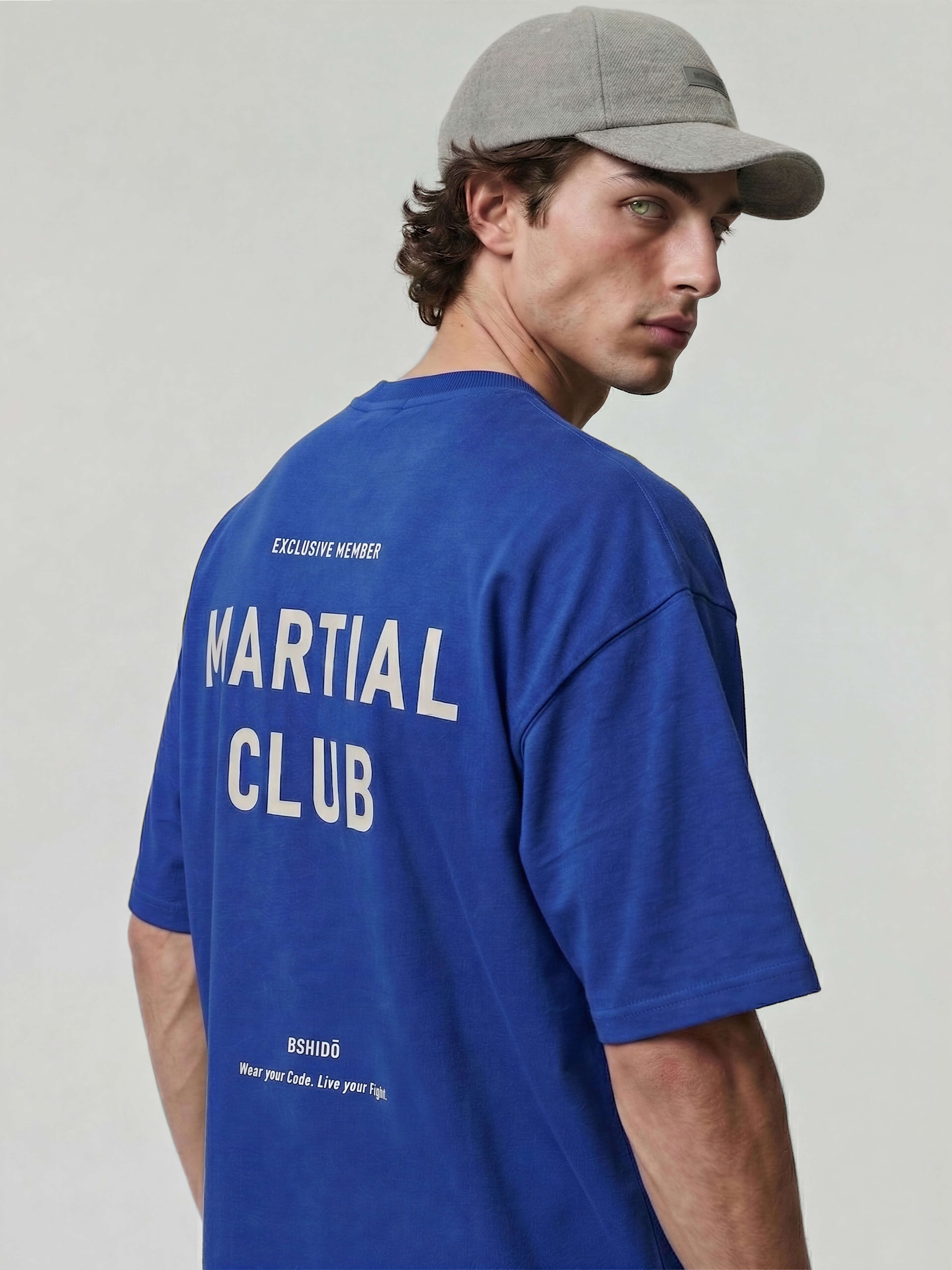 Blue oversized Bshido t-shirt back angled close-up showing “Martial Club” and “Exclusive Member” print
