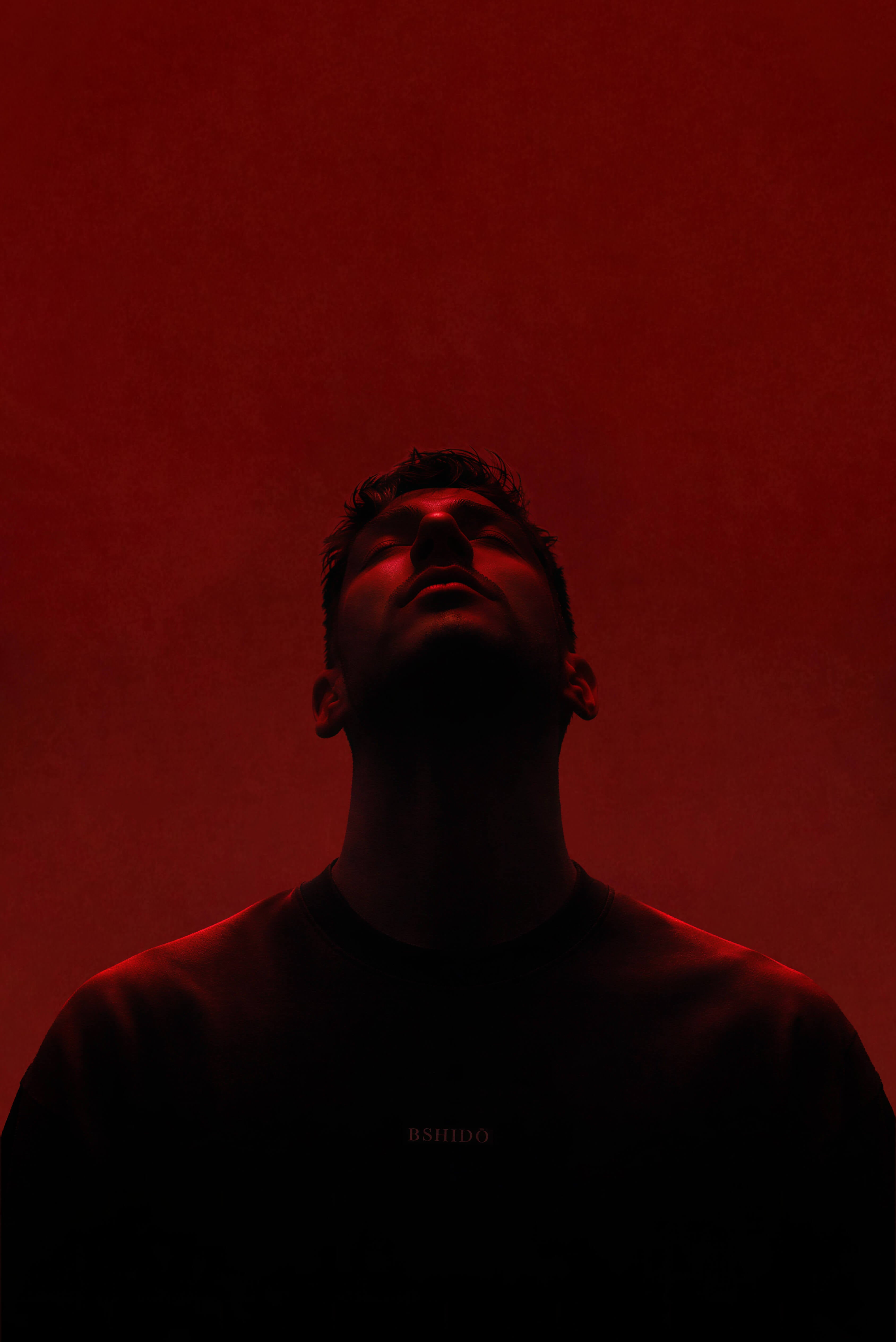 Man wearing Bshidō apparel looking upward under red lighting